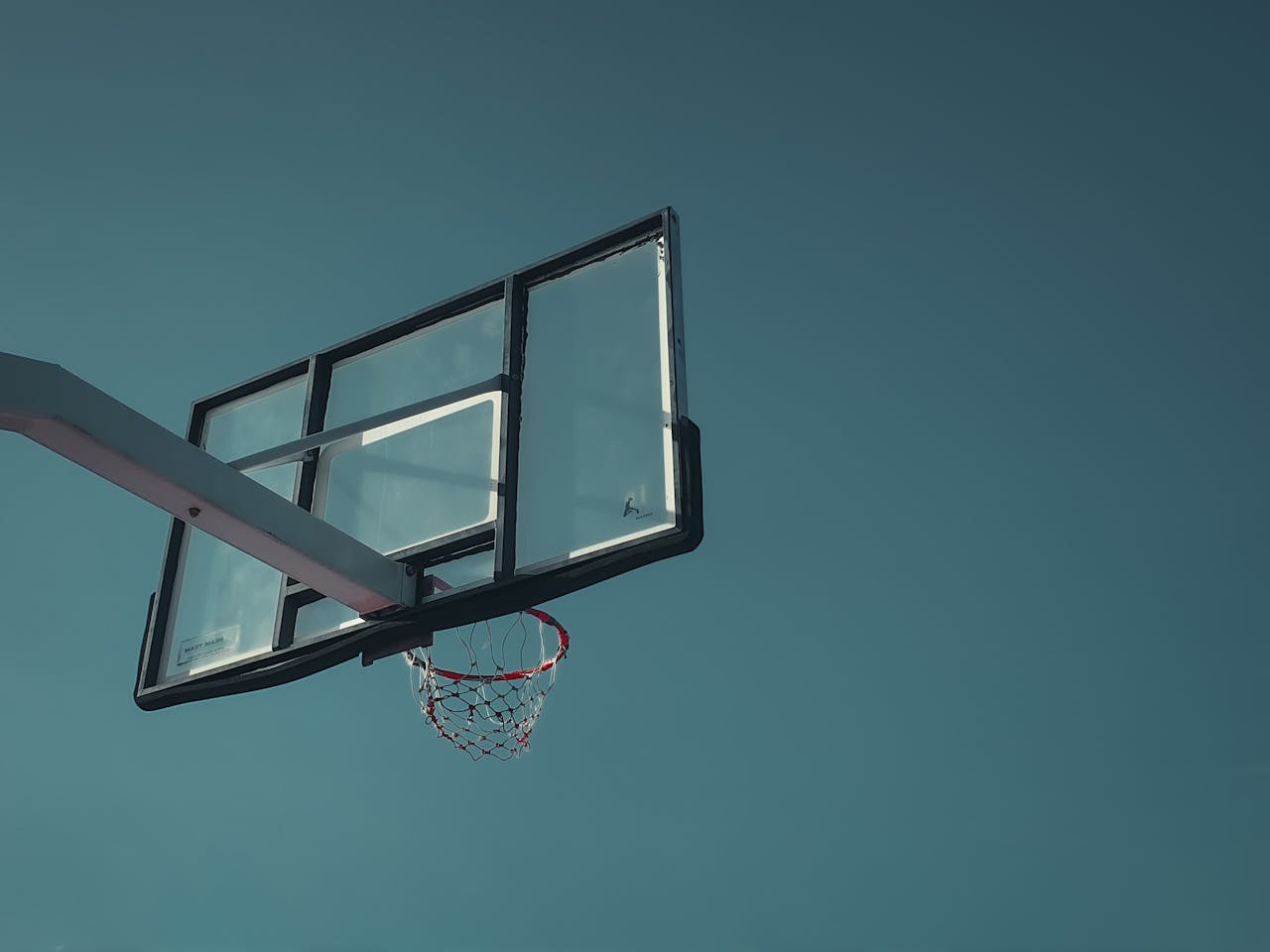 A minimalist view of a basketball hoop against a clear, serene sky.