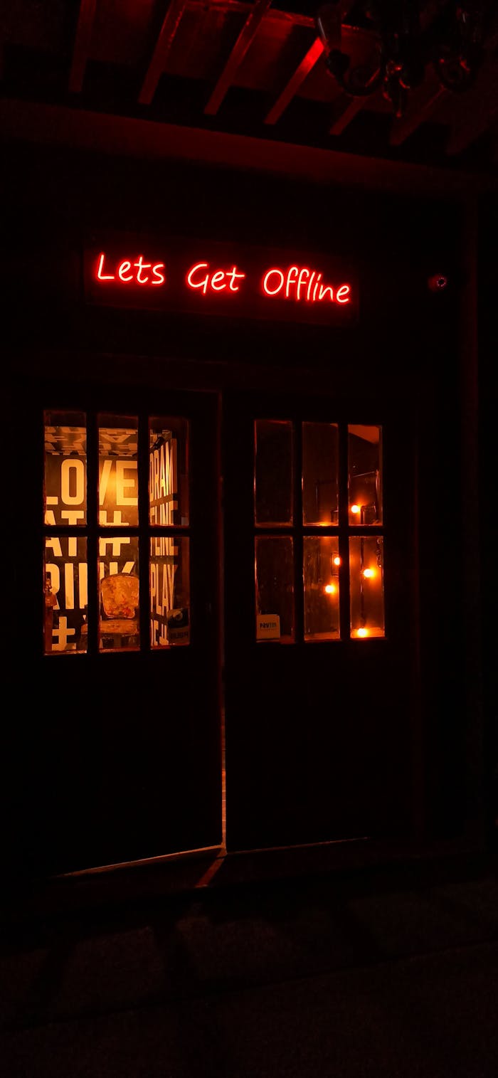 Illuminated neon sign 'Let's Get Offline' glows in a warm, cozy ambiance at night.